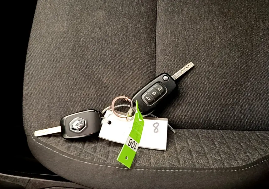 Gros plan sur les clés Renault posées sur un siège tissu gris foncé à motifs géométriques dans l'habitacle.