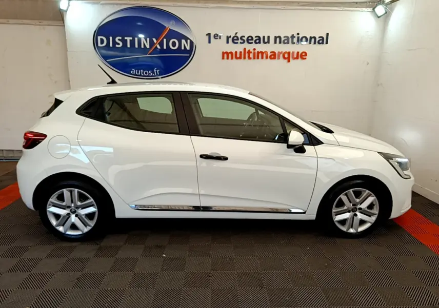 Profil côté gauche d'une Renault Clio Business blanche 2021, avec jantes alliage et poignées noires visibles en intérieur showroom.