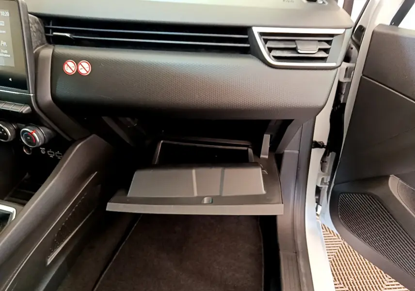 Vue intérieure côté passager de la Renault Clio Business blanche 2021, boîte ouverte du vide-poches et tableau de bord noir.