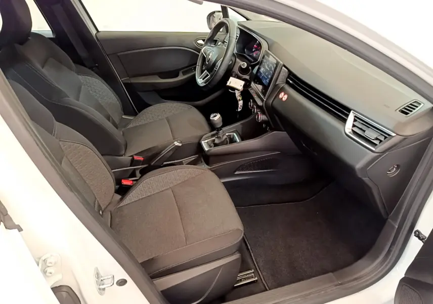 Intérieur côté droit d'une Renault Clio Business blanche, montrant sièges tissu, volant cuir et écran tactile central.
