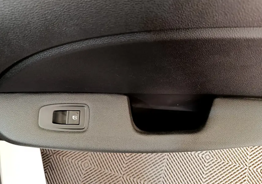 Gros plan sur la commande de verrouillage centralisé noire dans l'intérieur de la Renault Clio Business blanche.