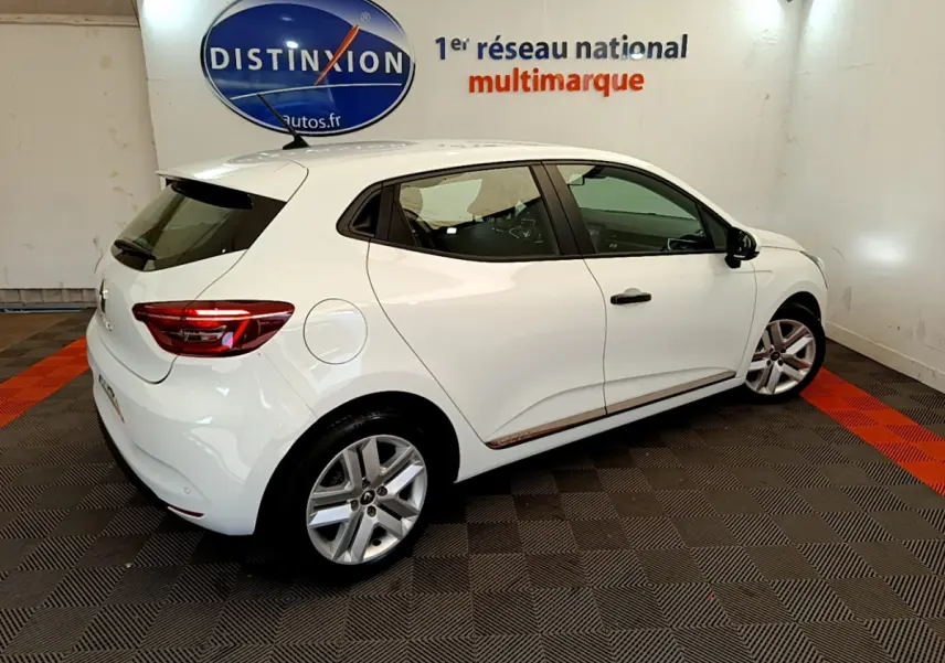 Vue 3/4 arrière droite d'une Renault Clio Business blanche, avec jantes alliage et logo Distinxion en arrière-plan.