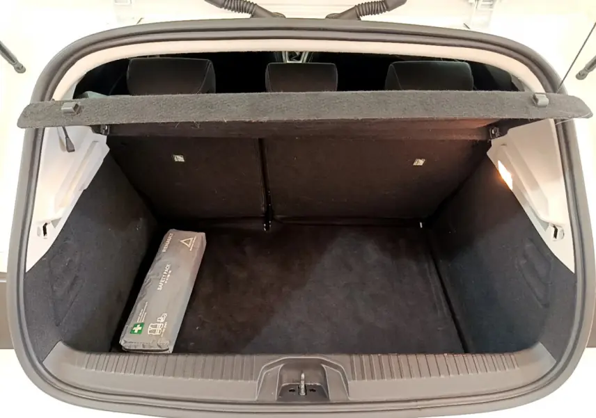 Coffre ouvert vu de l'arrière d'une Renault Clio Business blanche, avec cache-bagages et trousse de secours noire.