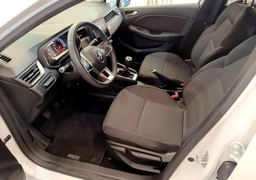 Intérieur avant droit de la Renault Clio Business blanche, sièges gris, volant cuir et tableau de bord avec écran tactile.