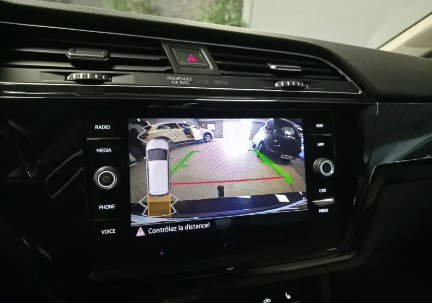 Écran tactile intérieur montrant la caméra de recul avec guidage vert et rouge du Volkswagen Touran bleu 2024.