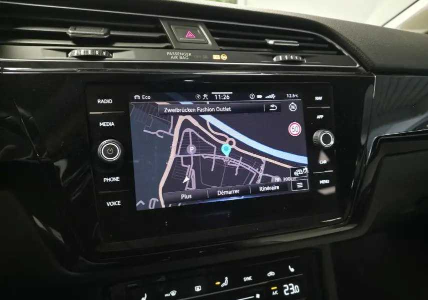 Écran tactile central du Volkswagen Touran 2024 affichant la navigation, entouré de commandes multimédia et climatisation.
