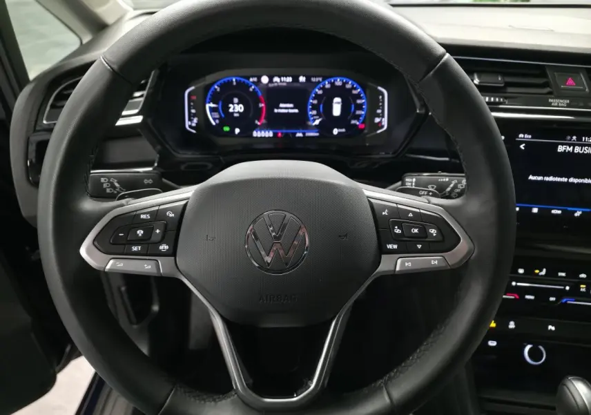 Gros plan sur le volant cuir multifonction noir du Volkswagen Touran 2024 avec tableau de bord numérique et écran tactile.