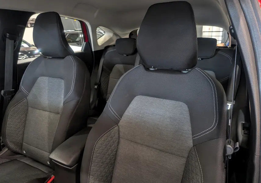 Intérieur du Renault Captur TCe 90 CH Zen 2023, vue sur les sièges avant en tissu gris et noir, porte rouge Flamme ouverte.
