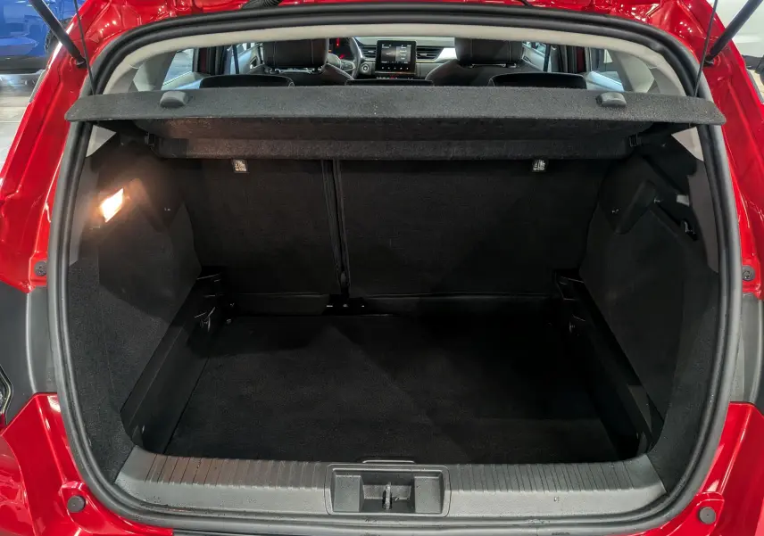 Coffre ouvert du Renault Captur TCe 90 CH Zen 2023 rouge flamme, vue arrière montrant l'espace de chargement noir.