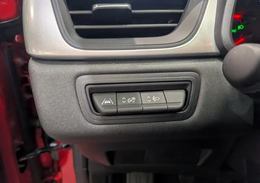 Gros plan sur les commandes d'assistance et éclairage du tableau de bord d'un Renault Captur Rouge Flamme 2023.