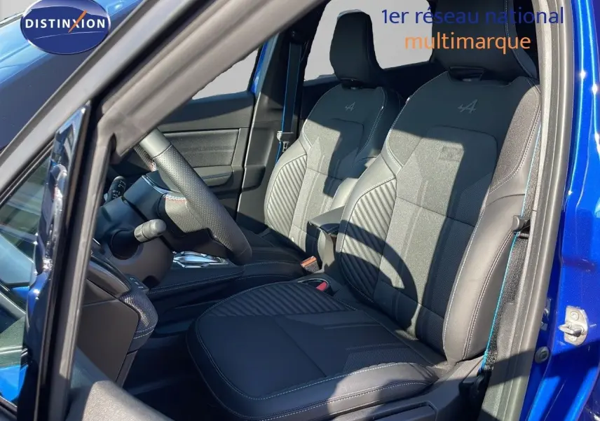 Intérieur côté conducteur du Renault Captur E-Tech hybride 2025, sièges noirs avec surpiqûres bleues et logo Alpine.