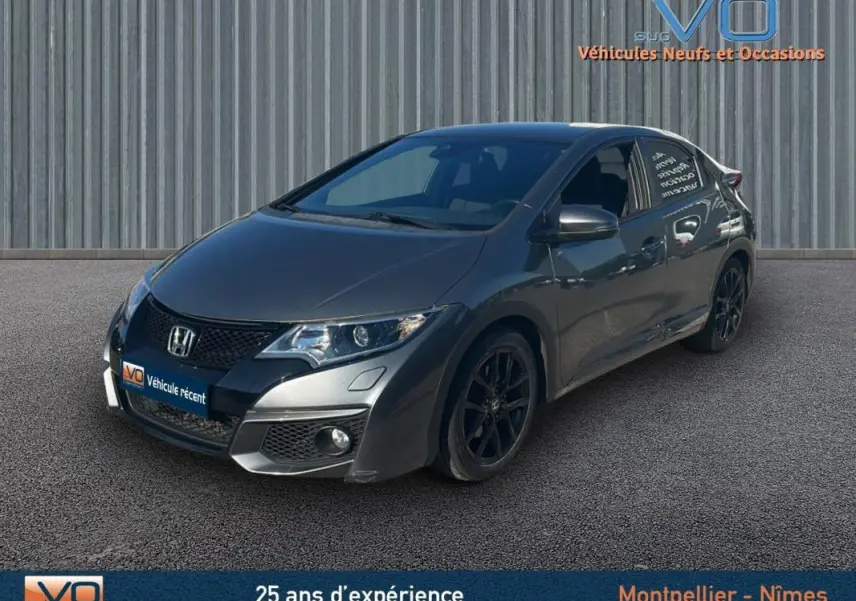 Vue 3/4 avant d'une Honda Civic gris foncé de 2015 avec jantes alliage noires et vitres surteintées.