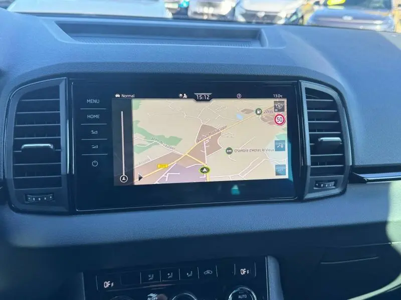 Vue rapprochée de l'écran tactile central du tableau de bord du Skoda Karoq gris avec navigation GPS affichée.