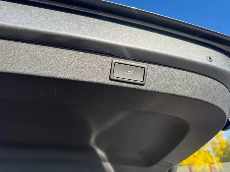 Bouton d'ouverture électrique du coffre sur la partie intérieure du hayon d'un Skoda Karoq gris.