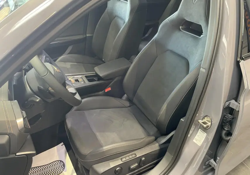 Vue intérieure côté conducteur d'une CUPRA Leon gris Graphène, sièges baquets suédine noire avec surpiqûres cuivrées et volant cuir.