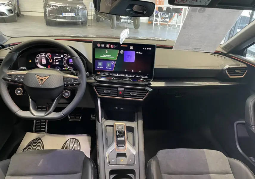 Vue intérieure avant du CUPRA Leon 2026 avec tableau de bord numérique, volant cuir et écran tactile central.