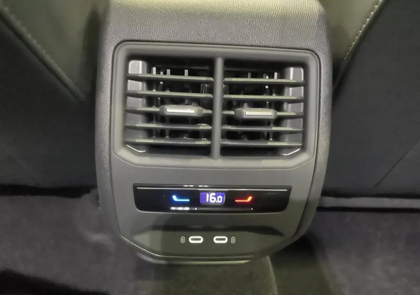 Gros plan sur la console arrière avec réglage climatisation à 16°C et deux prises USB-C, intérieur noir suédine.