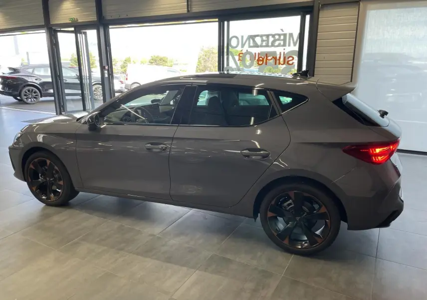 Vue latérale droite d'une CUPRA Leon 2.0 TDI gris Graphène avec jantes alliage 18'' cuivrées en showroom.