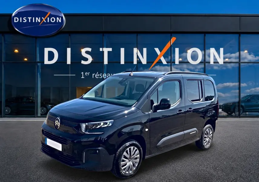 Citroën Berlingo noir vue 3/4 avant droit, avec barres de toit et jantes alu devant showroom Distinxion.