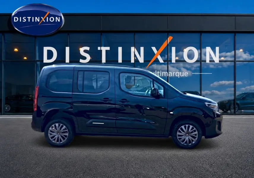 Profil droit d'un Citroën Berlingo noir 2026 garé devant une vitrine avec logo Distinxion.