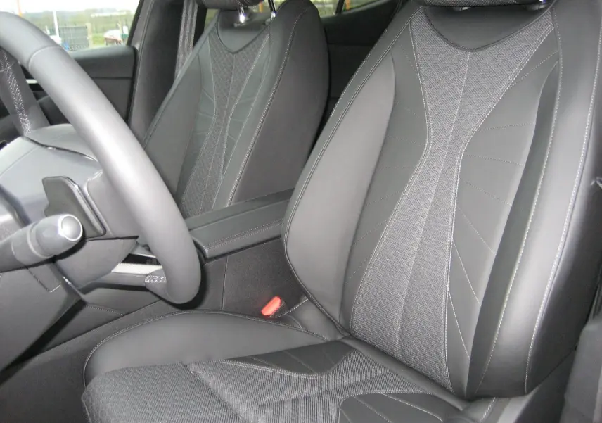 Gros plan sur les sièges avant en cuir et tissu gris du DS4 2024, avec volant partiellement visible côté gauche.