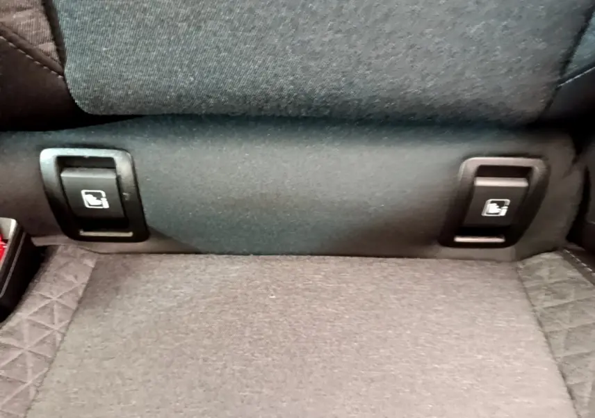 Gros plan sur les commandes de rabattement des sièges arrière en tissu gris de la Renault Clio Business blanche.