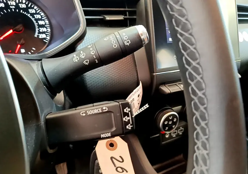 Gros plan sur le volant et commandes au volant d'une Renault Clio Business blanche, tableau de bord et écran tactile visibles.