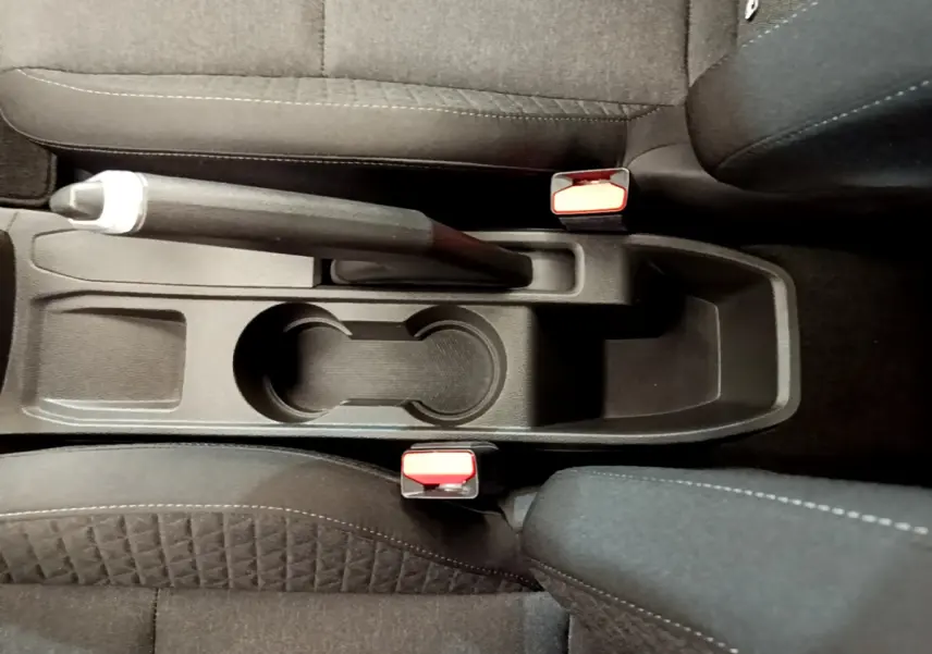 Vue plongeante sur la console centrale noire de la Renault Clio Business 2021, avec frein à main manuel et porte-gobelets.