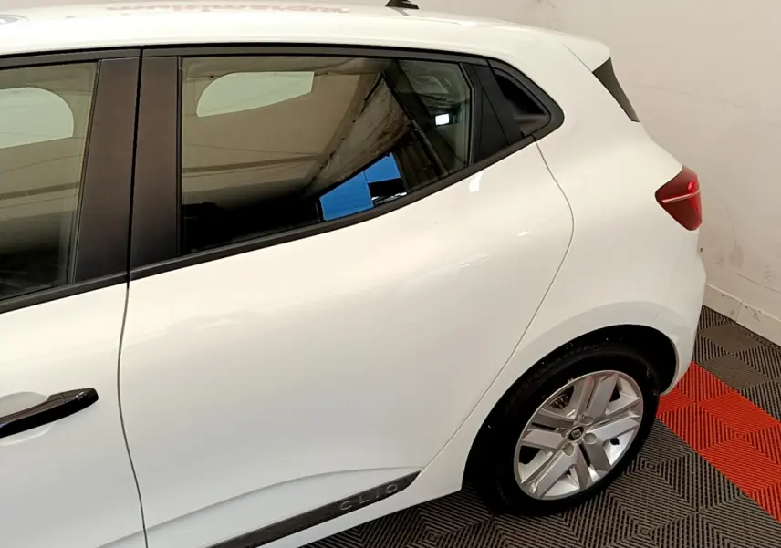Vue latérale côté droit d'une Renault Clio Business blanche, mettant en valeur la ligne de caisse et la jante alliage.