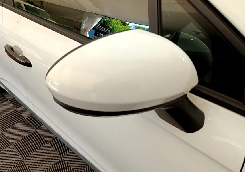 Rétroviseur droit blanc en gros plan sur une Renault Clio Business 2021, porte et poignée visibles en arrière-plan.