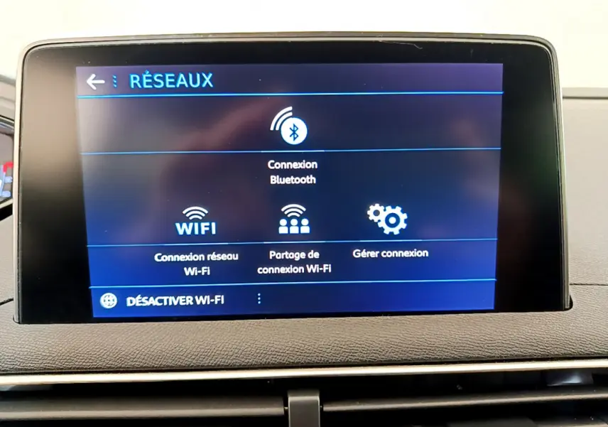 Écran tactile central affichant les options réseau Bluetooth et Wi-Fi dans l’habitacle d’un Peugeot 3008 gris foncé.