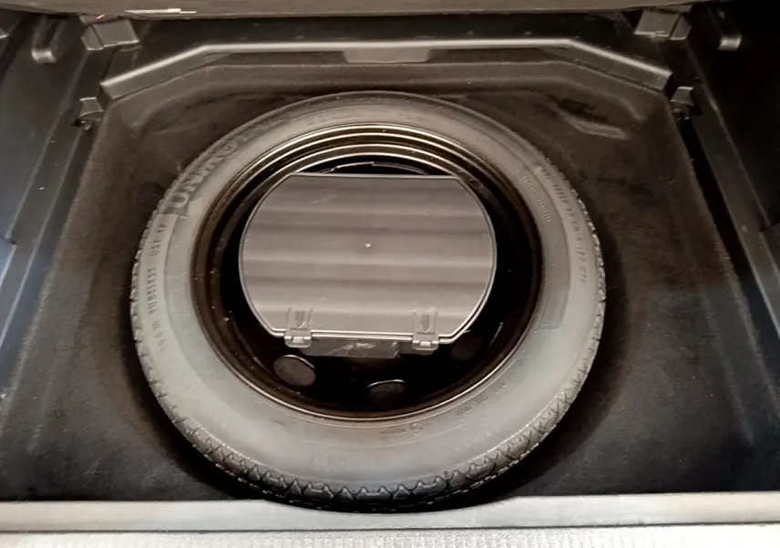 Vue plongeante sur la roue de secours et le rangement sous tablette dans le coffre du Peugeot 3008 gris foncé.