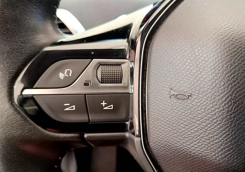 Gros plan sur les commandes gauche du volant cuir noir du Peugeot 3008 gris foncé Puretech 130 S&S Active 2020.