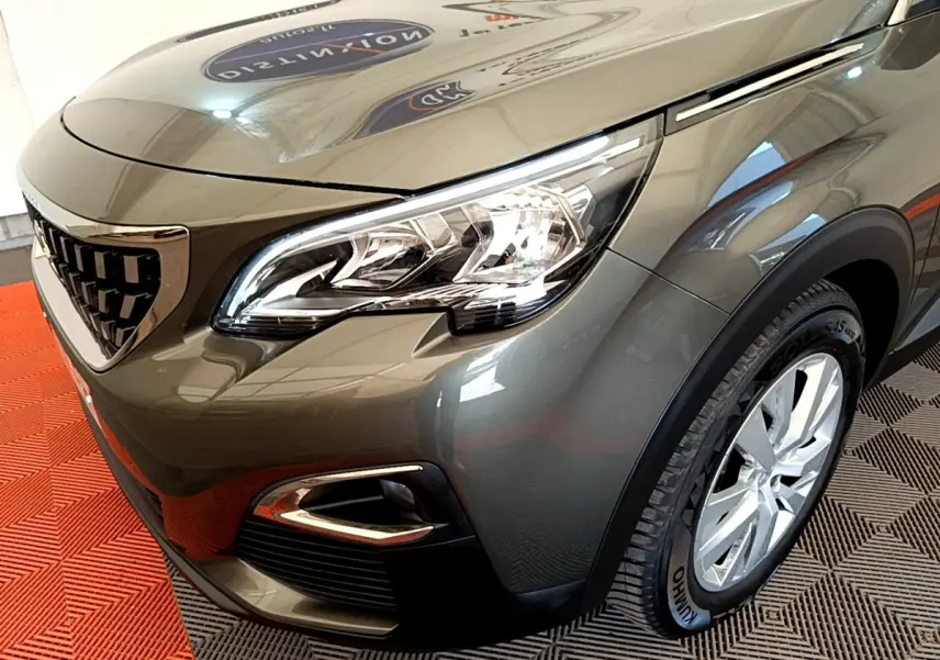 Vue 3/4 avant droit du Peugeot 3008 gris foncé, mettant en valeur le phare LED et la calandre distinctive.