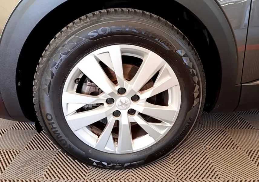 Gros plan sur la roue avant gauche d’un Peugeot 3008 gris foncé, mettant en valeur la jante alliage et le pneu Kumho.