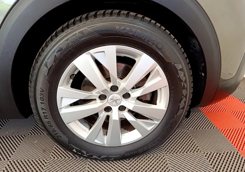 Gros plan sur la roue avant droite d’un Peugeot 3008 gris foncé, avec jante argentée et pneu Kumho.