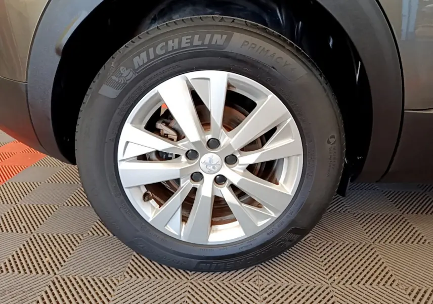 Gros plan sur la roue avant droite d’un Peugeot 3008 gris foncé, avec jante alliage et pneu Michelin Primacy 4.