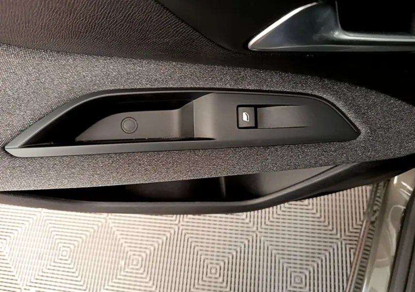 Détail de la commande de lève-vitre sur la porte intérieure côté conducteur d’un Peugeot 3008 gris foncé 2020.