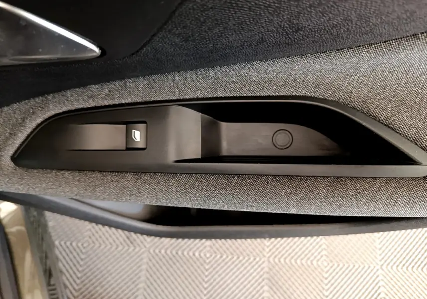 Détail de la commande de lève-vitre sur la porte côté conducteur du Peugeot 3008 gris foncé, intérieur tissu.