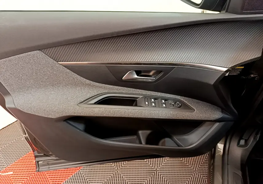 Vue intérieure côté gauche de la porte avant d’un Peugeot 3008 gris foncé avec commandes électriques et garniture texturée.