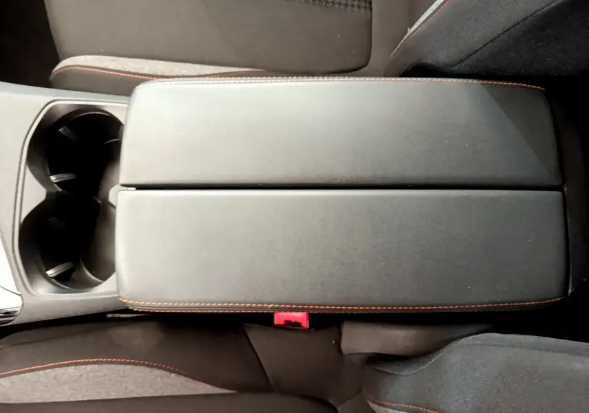 Vue plongeante sur l'accoudoir central noir avec surpiqûres orange et porte-gobelets du Peugeot 3008 gris foncé 2020.