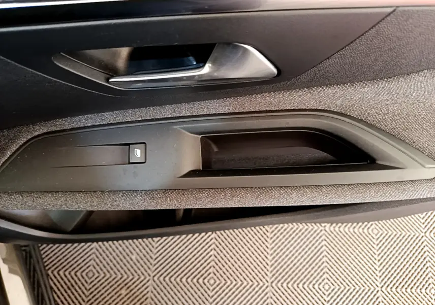 Détail de la poignée intérieure côté conducteur du Peugeot 3008 gris foncé, avec bouton de verrouillage des portes.