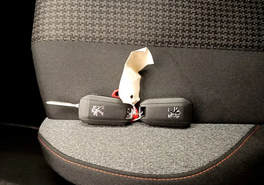 Gros plan sur deux clés Peugeot posées sur un siège tissu gris foncé avec surpiqûres rouges à l'intérieur d'un Peugeot 3008.