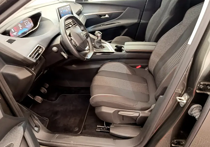 Intérieur avant droit du Peugeot 3008 gris foncé 2020, volant cuir, tableau de bord numérique et boîte manuelle.