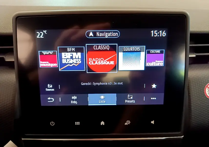 Écran tactile central allumé de la Renault Clio Business blanche, affichant les stations radio et la navigation.
