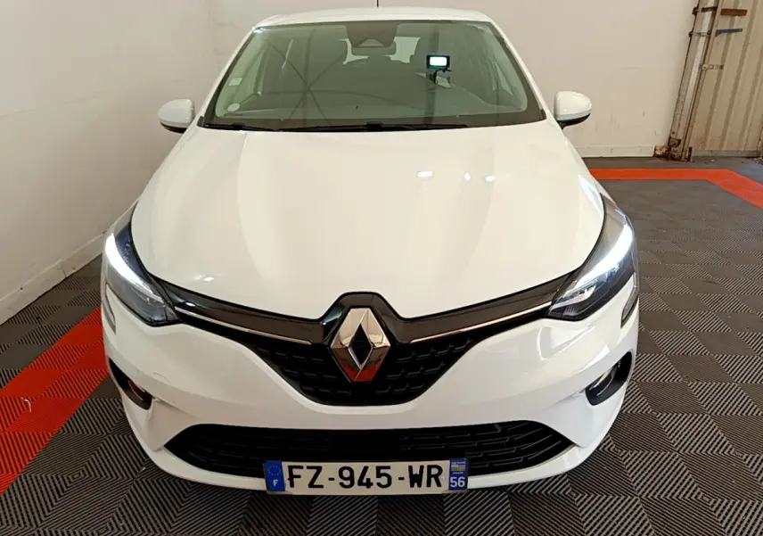 Vue de face d'une Renault Clio Business blanche avec phares LED allumés dans un garage.