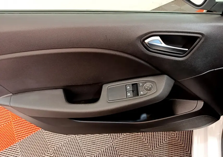 Vue rapprochée de la porte avant gauche noire de la Renault Clio Business blanche, avec commandes électriques et poignée chromée.