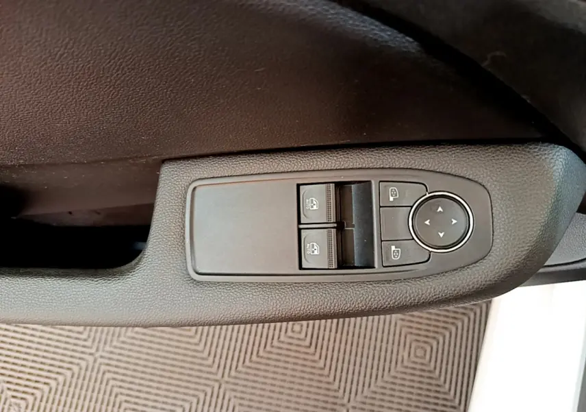 Gros plan sur les commandes de lève-vitres et réglage des rétroviseurs côté conducteur d'une Renault Clio blanche 2021