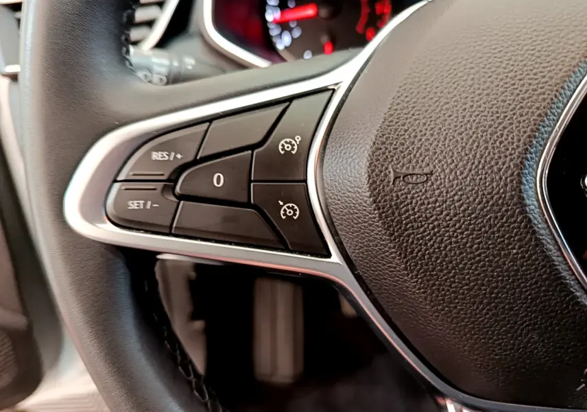 Gros plan sur le volant cuir synthétique de la Renault Clio Business blanc, avec commandes de régulateur de vitesse visibles.