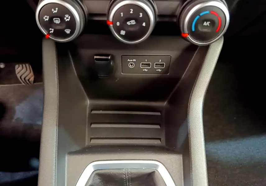 Gros plan sur la console centrale noire de la Renault Clio Business avec commandes de climatisation et ports USB visibles